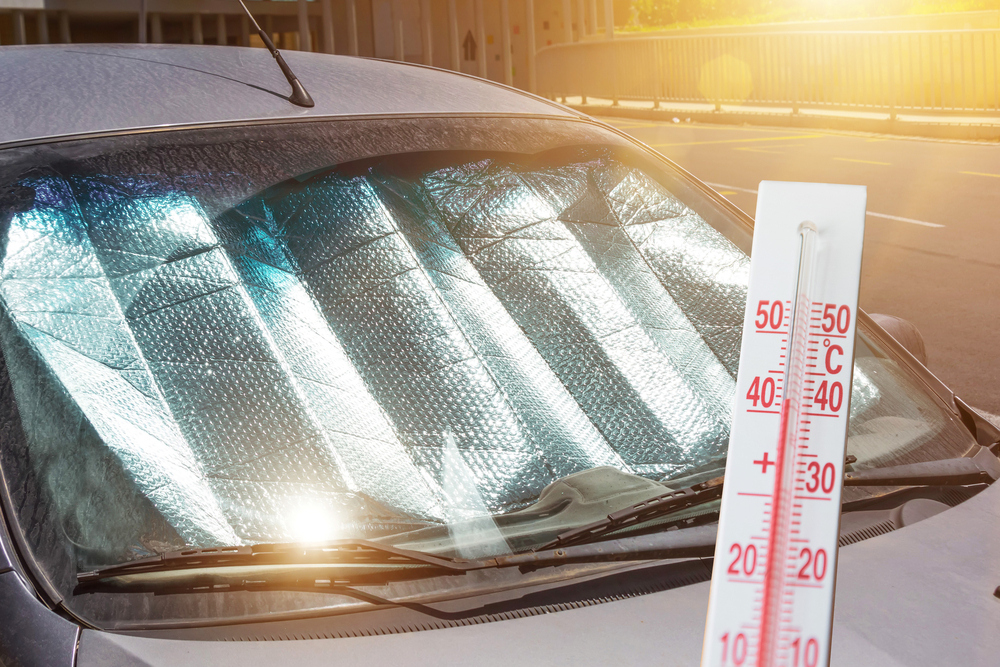 Auto met zonnescherm staat buiten in hoge temperatuur.